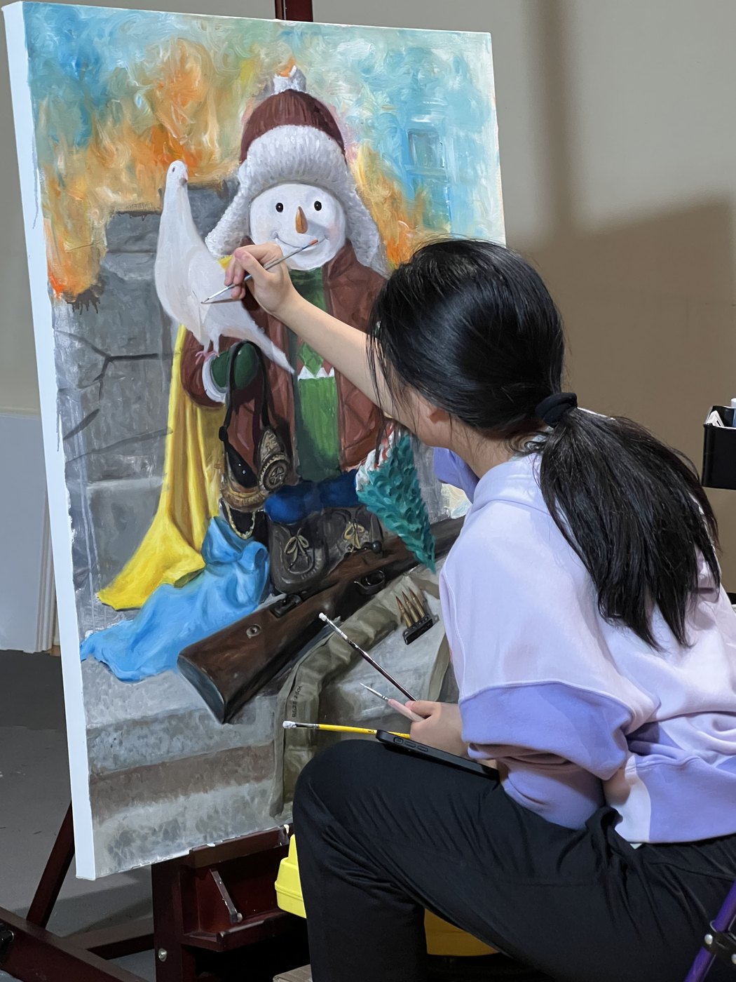 The artist at her easel, working on an oil painting.